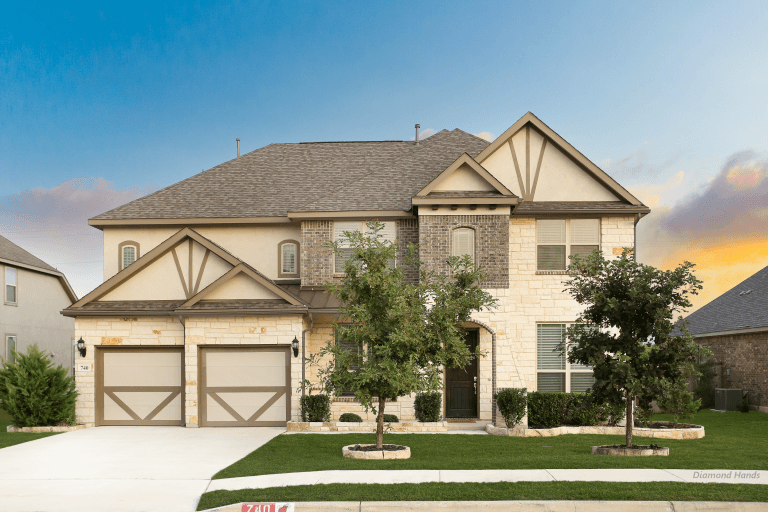 Exterior of large tan house with 2 car garage, large windows, and green grass used as a TDY Crashpad in Randolph AFB.