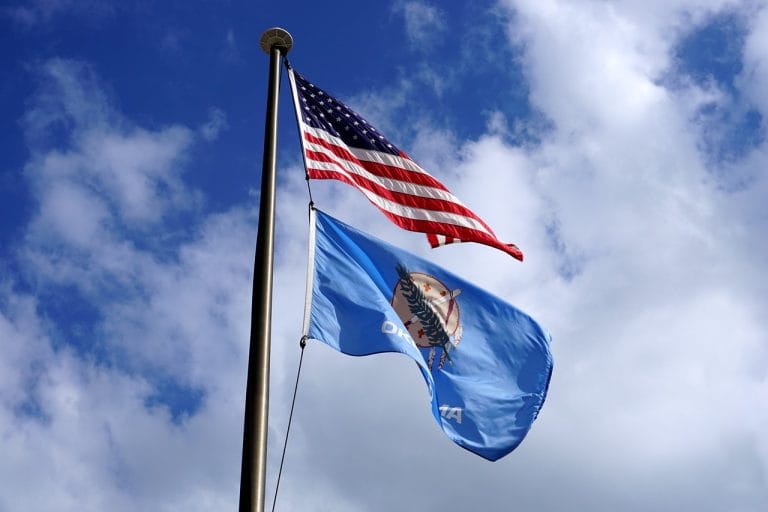 United States flag waving above an Oklahoma State flag with a blue sky at Altus AFB