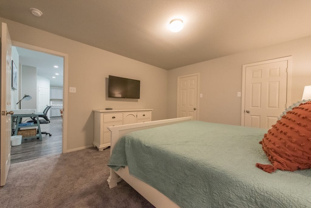 Cozy bedroom with plush carpet, a stylish bed, modern TV, and dedicated workspace perfect for relaxation or productivity | Dream TDY