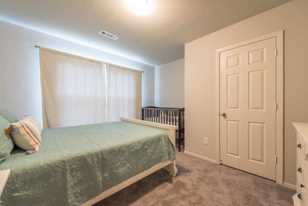 Cozy bedroom with soft carpet, chic furniture, nursery crib, and natural light. Perfect for families or solo stays | Dream TDY