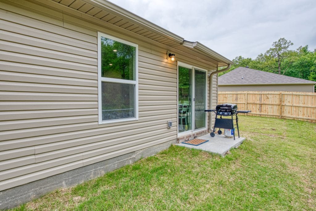 Cozy outdoor space with a grill, perfect for relaxation. Clean exterior and peaceful yard enhance your stay | Dream TDY