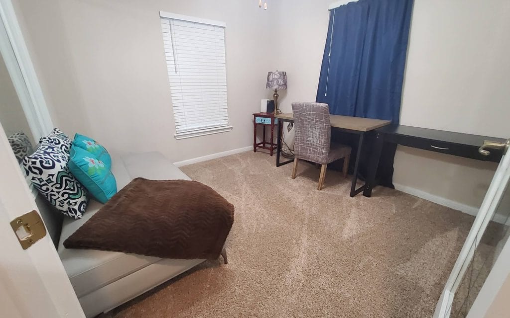 Cozy bedroom with stylish furnishings, dedicated workspace, and plush carpet; perfect for relaxing after a long day | Dream TDY