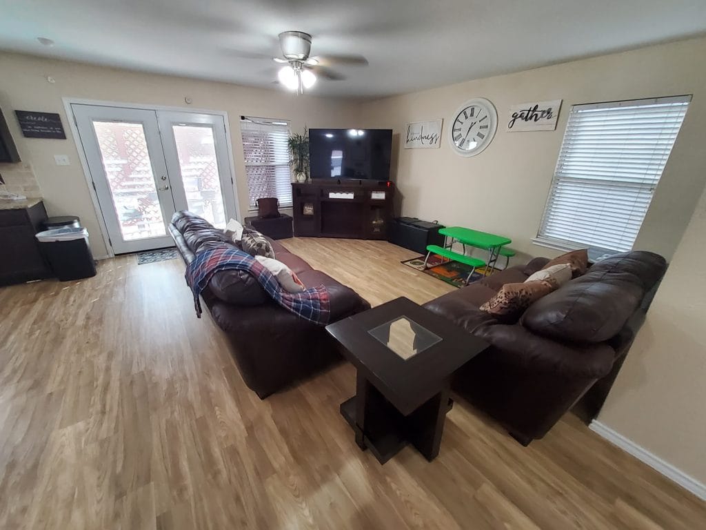 Bright and inviting living area with cozy leather sofas, modern TV, and a dedicated workspace. Clean, with outdoor access | Dream TDY