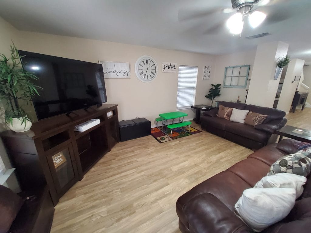 Spacious living area with leather couches, large TV, and a cozy children's play table. Modern decor and bright ambiance enhance comfort | Dream TDY