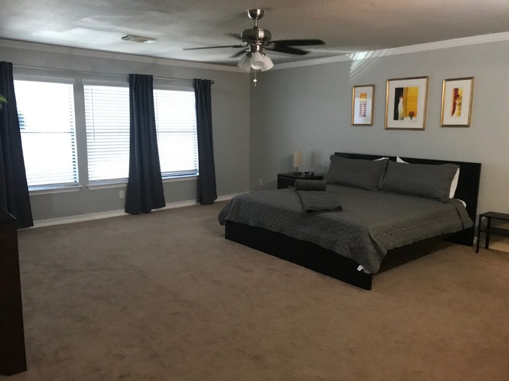 Spacious and clean bedroom with modern decor, ceiling fan, and ample natural light. Perfect for relaxation | Dream TDY