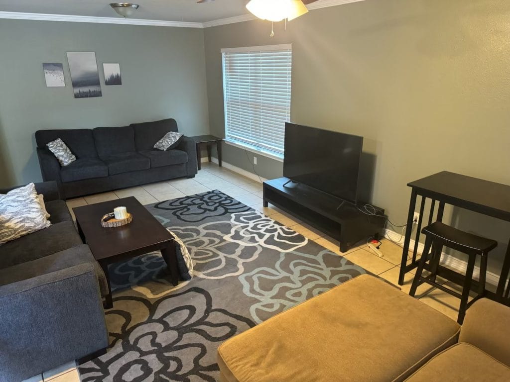 Cozy living room with modern furniture, large TV, dedicated workspace, and inviting ambiance | Dream TDY