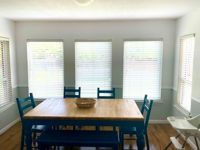 Bright dining area with a wooden table, cozy blue chairs, and ample natural light. Perfect for family meals | Dream TDY