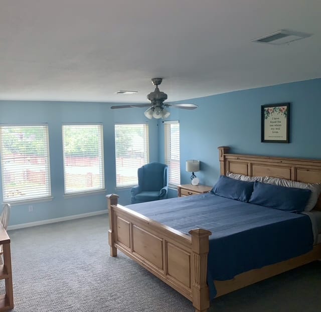 Spacious bedroom with inviting blue walls, comfortable king bed, dedicated workspace, and bright natural light | Dream TDY
