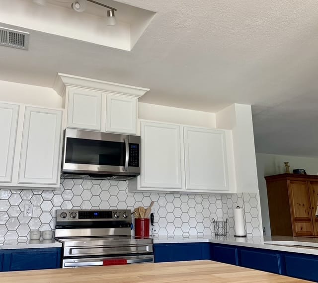Modern kitchen with sleek stainless steel appliances, white cabinetry, and a cozy atmosphere perfect for meal prep | Dream TDY
