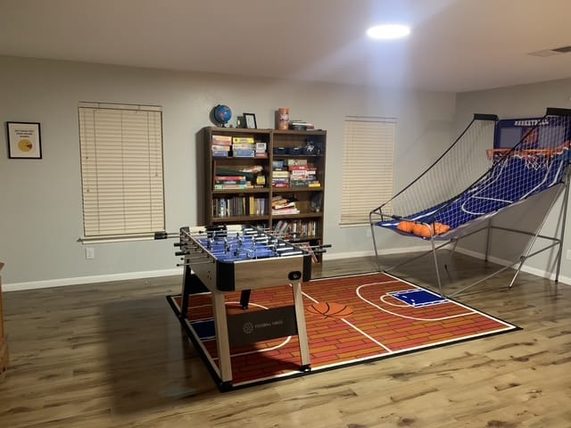 Spacious game room with foosball table, cozy seating, bookshelves, and a fun basketball-themed rug | Dream TDY