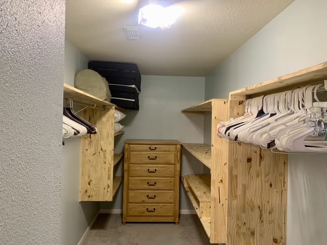 Spacious walk-in closet with wooden shelving, organized space, and ample storage for a comfortable stay | Dream TDY