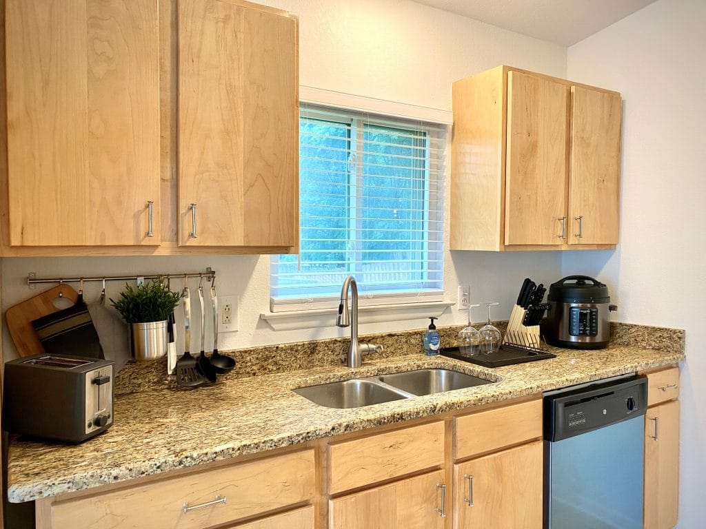 Modern kitchen with sleek appliances, granite countertops, and ample storage; perfect for a short-term military stay | Dream TDY
