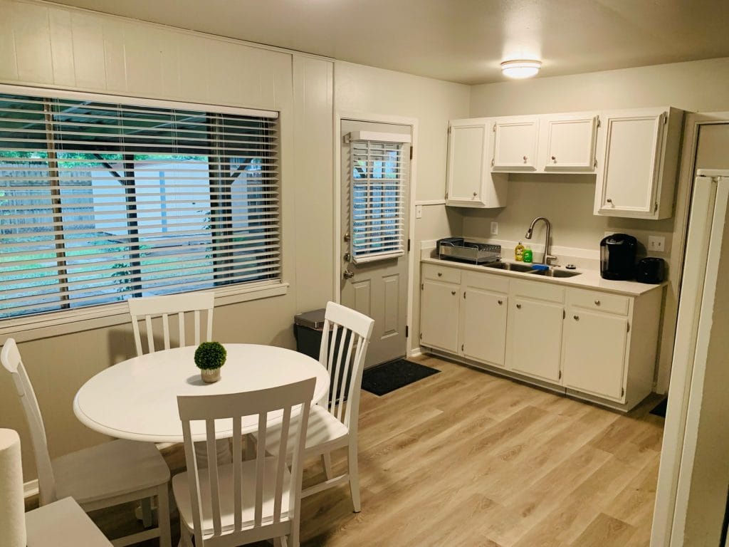 Bright kitchen with modern appliances, clean white cabinetry, a cozy dining space, and easy outdoor access | Dream TDY