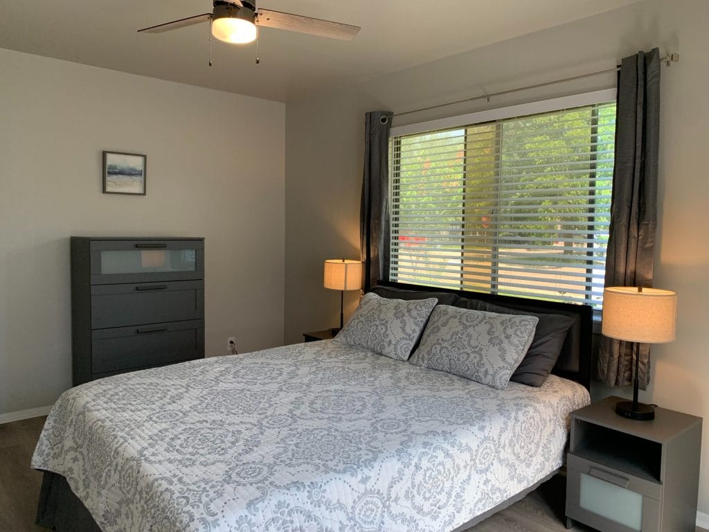 Bright and cozy bedroom featuring a queen bed, modern furniture, ample natural light, and a dedicated workspace | Dream TDY