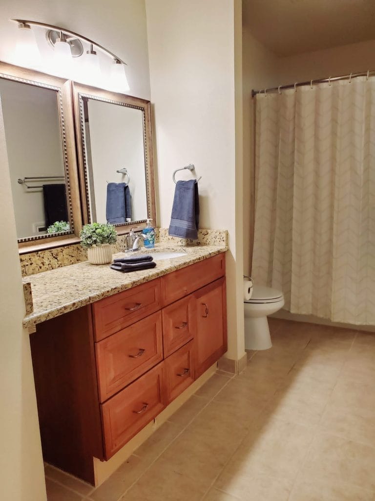 Modern bathroom with elegant granite vanity, spacious mirrors, and sleek fixtures. Clean and well-maintained for ultimate comfort | Dream TDY