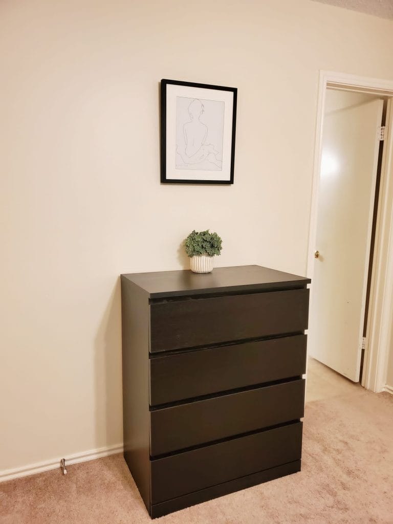 Stylish and clean bedroom with modern dresser, plush carpet, and minimalistic decor. Perfect for a relaxing stay | Dream TDY