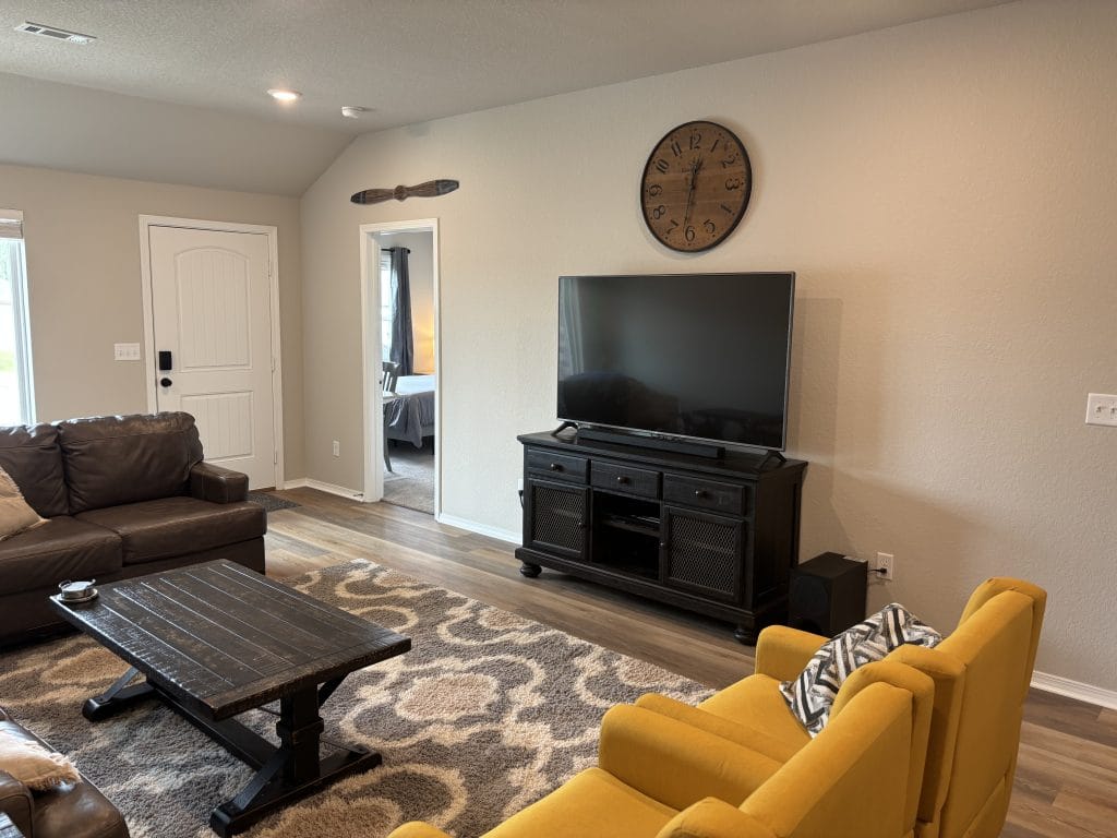 Spacious living area featuring cozy seating, modern TV, and vibrant accents. Enjoy a comfortable, clean environment perfect for relaxation.
