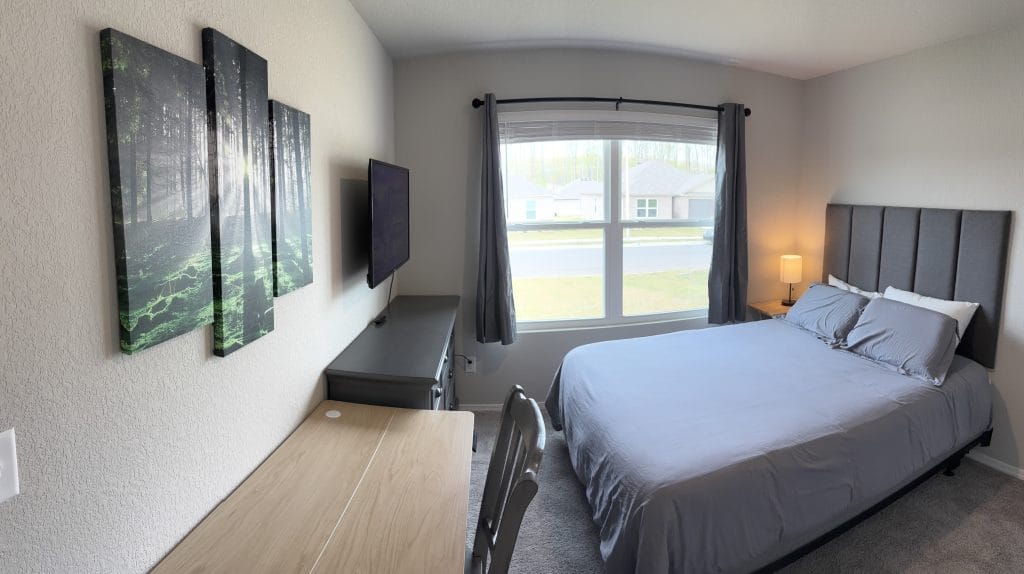Cozy bedroom with modern decor, a dedicated workspace, TV, and bright natural light—perfect for short-term military stays.