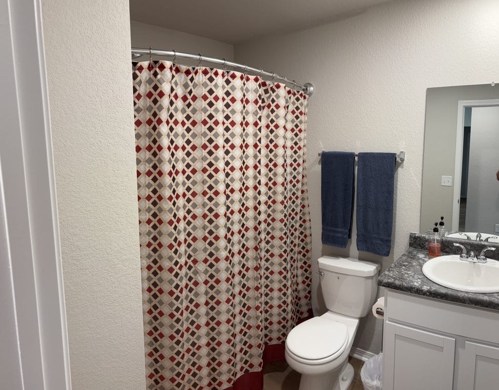 Bright and clean bathroom features modern fixtures, a stylish shower curtain, and convenient towels, ensuring a relaxing stay.