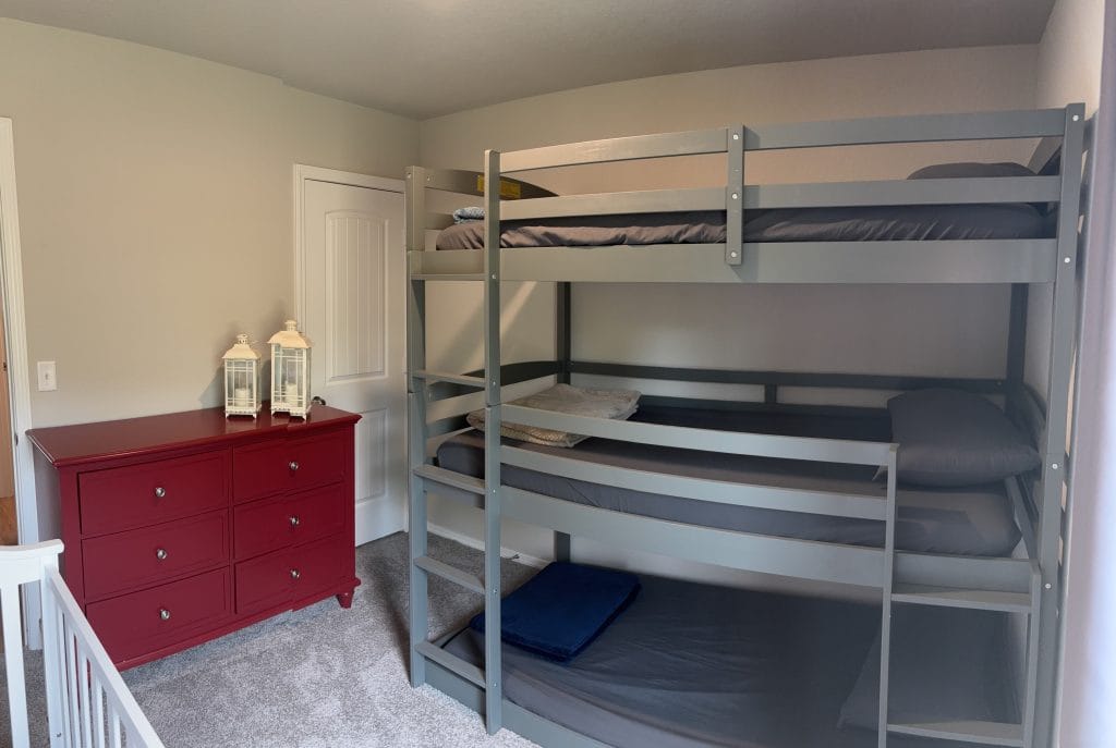 Cozy bunk room featuring a stylish dresser, plush carpet, and ample storage—perfect for short-term military stays.