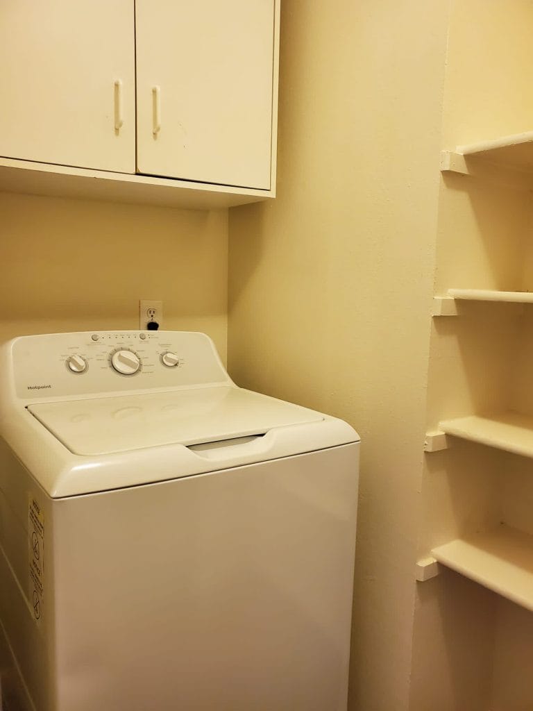 Bright laundry area with modern washer, ample shelving, and cabinets for storage | Dream TDY