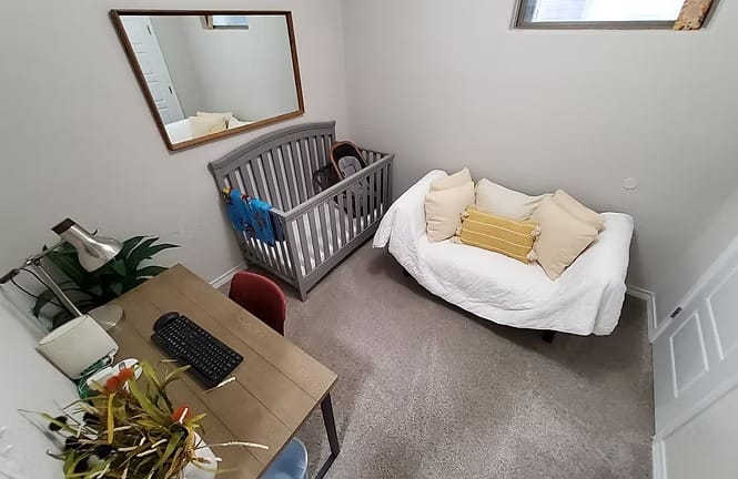 Cozy room featuring a dedicated workspace, crib, and stylish seating, all in a clean, inviting space | Dream TDY