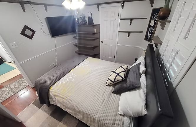 Cozy bedroom with modern decor, a comfy bed, wall-mounted TV, and ample storage; perfect for short-term stays | Dream TDY