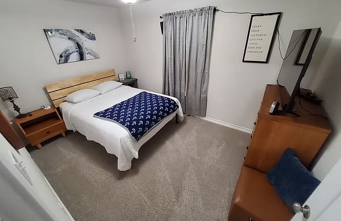 Cozy bedroom with plush carpet, a comfy bed, and a TV. Perfect for relaxation, featuring modern decor and clean amenities | Dream TDY