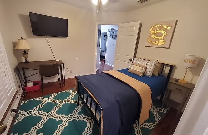 Cozy bedroom with a comfortable bed, desk for work, modern TV, and stylish decor | Dream TDY