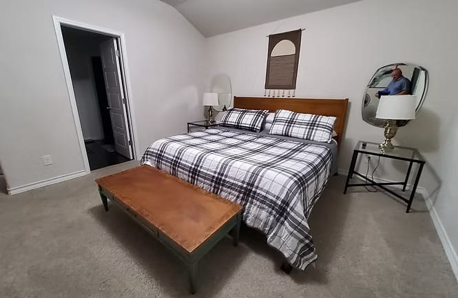 Cozy bedroom featuring a queen bed with plaid bedding, clean design, stylish lamps, and a functional workspace | Dream TDY