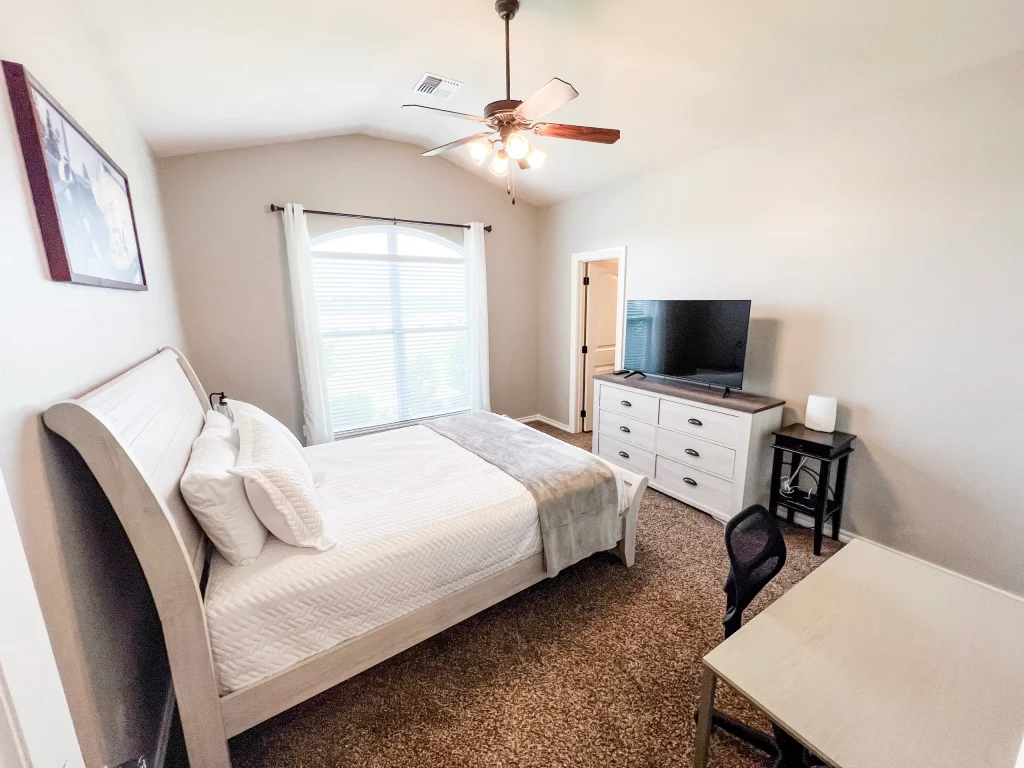 Cozy bedroom featuring a comfortable bed, modern TV, dedicated workspace, and ample natural light | Dream TDY