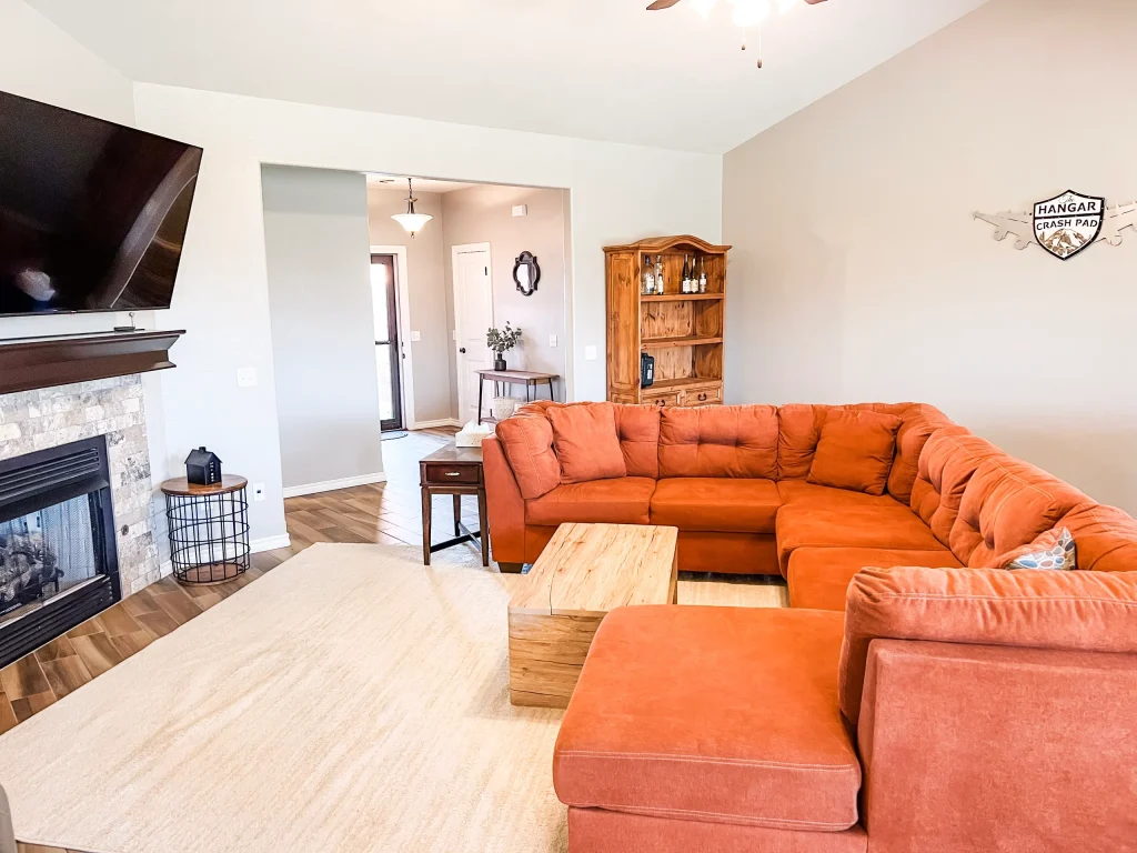 Spacious living area featuring a cozy sectional sofa, modern decor, and a dedicated workspace with a fireplace for relaxation | Dream TDY