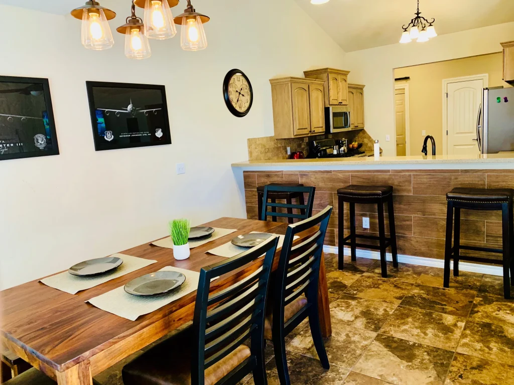 Inviting dining area features modern furniture, a spacious table for meals, and a sleek kitchen countertop with appliances | Dream TDY