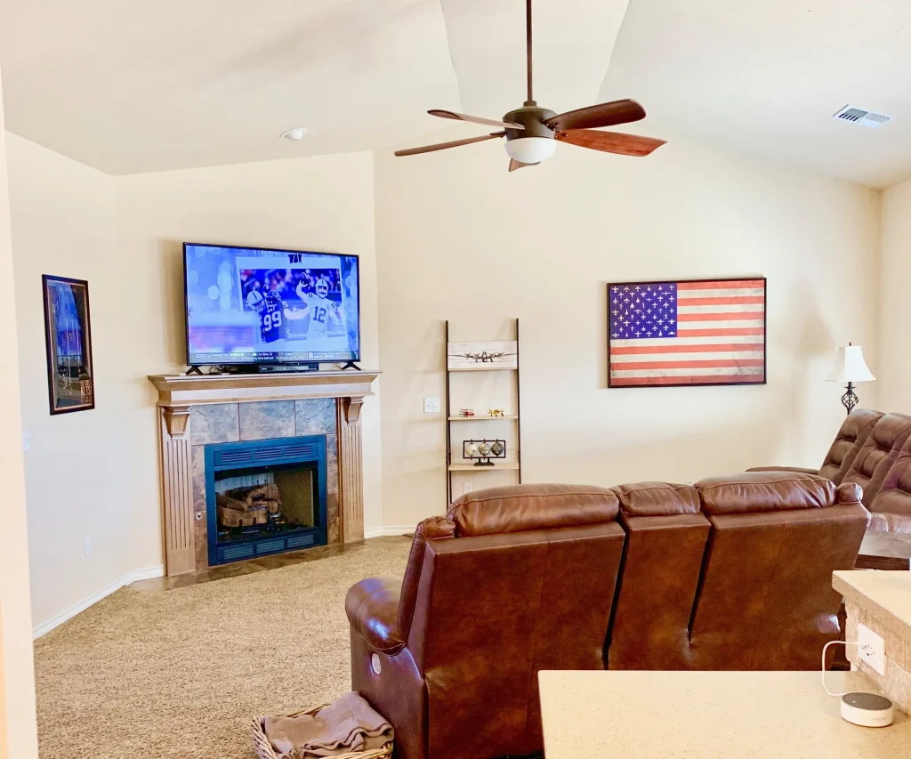 Spacious living area with cozy leather seating, modern TV, fireplace, and American decor. Perfect for relaxation | Dream TDY