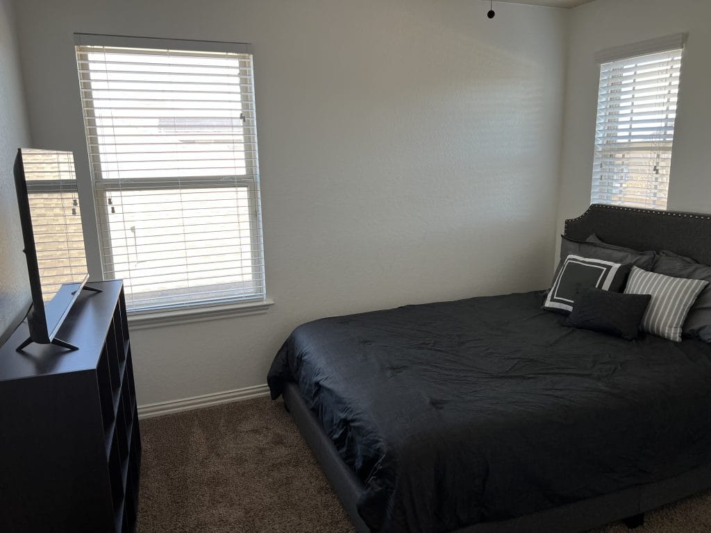 Cozy bedroom with plush bedding, a sleek TV, and ample natural light. Perfect for relaxation| Dream TDY