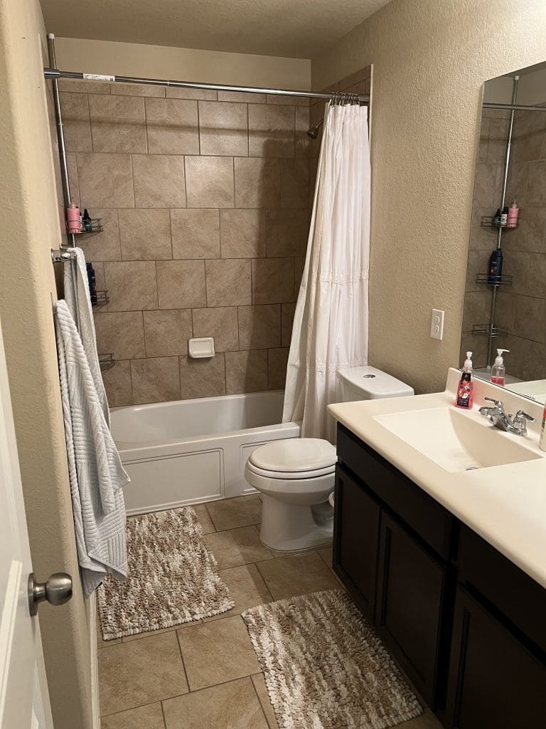 Spacious and clean bathroom featuring modern tiles, plush rugs, and a relaxing tub/shower combo | Dream TDY